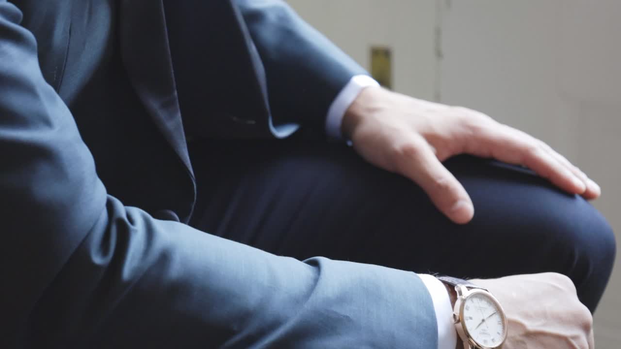 高価なスーツを着て一人で座る男性。
