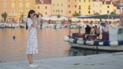 woman taking photos in a coastal town harbor