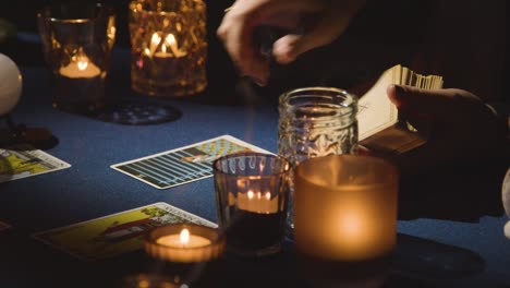 close up of woman giving tarot card reading on candlelit table holding the devil card