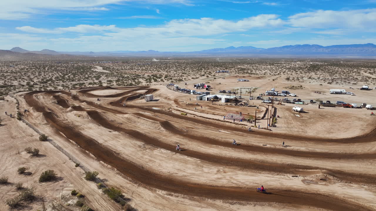 carreras de motocicletas en una pista de tierra con el paisaje arrollador del desierto de mojave en el fondo - gran altitud, vista aérea de gran angular