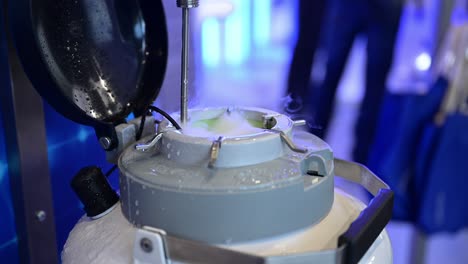 steam and gases of liquid nitrogen come from an open pressure vessel, close up, blue science background, zoom in