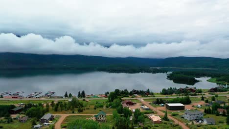 Aerial-Drone-View-of-Beautiful-Shadow-Mountain-Reservoir-on-a-Cloudy-Summer-Day-in-Grand-Lake-Colorado-with-Cars-Driving-on-Highway-Road-Along-Past-Vacation-Homes-the-Overcast-Shoreline