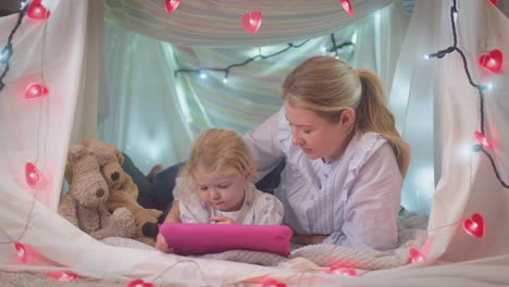 Madre-E-Hija-Pequeña-Con-Tableta-Digital-En-Un-Campamento-Casero-En-El-Dormitorio-De-Un-Niño-En-Casa---Filmadas-En-Cámara-Lenta