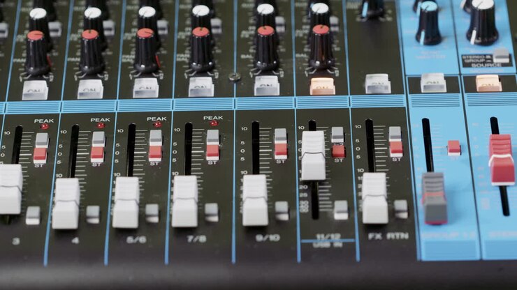 Closeup of a finger pushing a button on an audio mixer