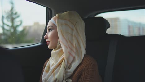 woman in hijab looking out car window