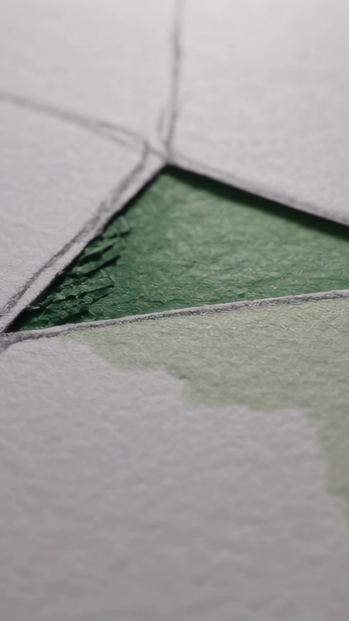 Vertical video: Shifting cam zooming in on textured paper green triangle, revealing pencil lines