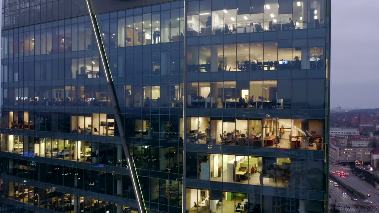 Drone shot at a night skyscraper with office windows