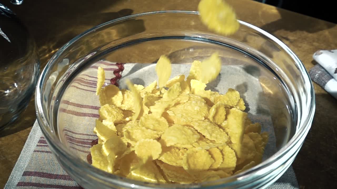 Fiocchi di mais gialli croccanti nella ciotola per una deliziosa colazione mattutina con latte. Slow motion con ripresa rotatoria.