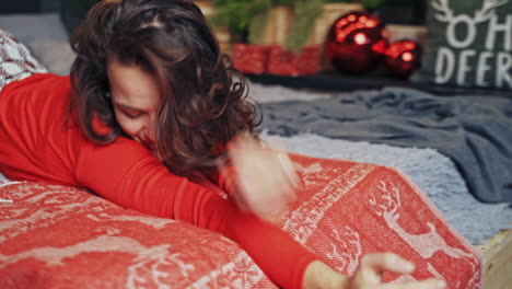 cute brunette laying and posing on bed before winter holidays. happy woman is waiting for fest time.