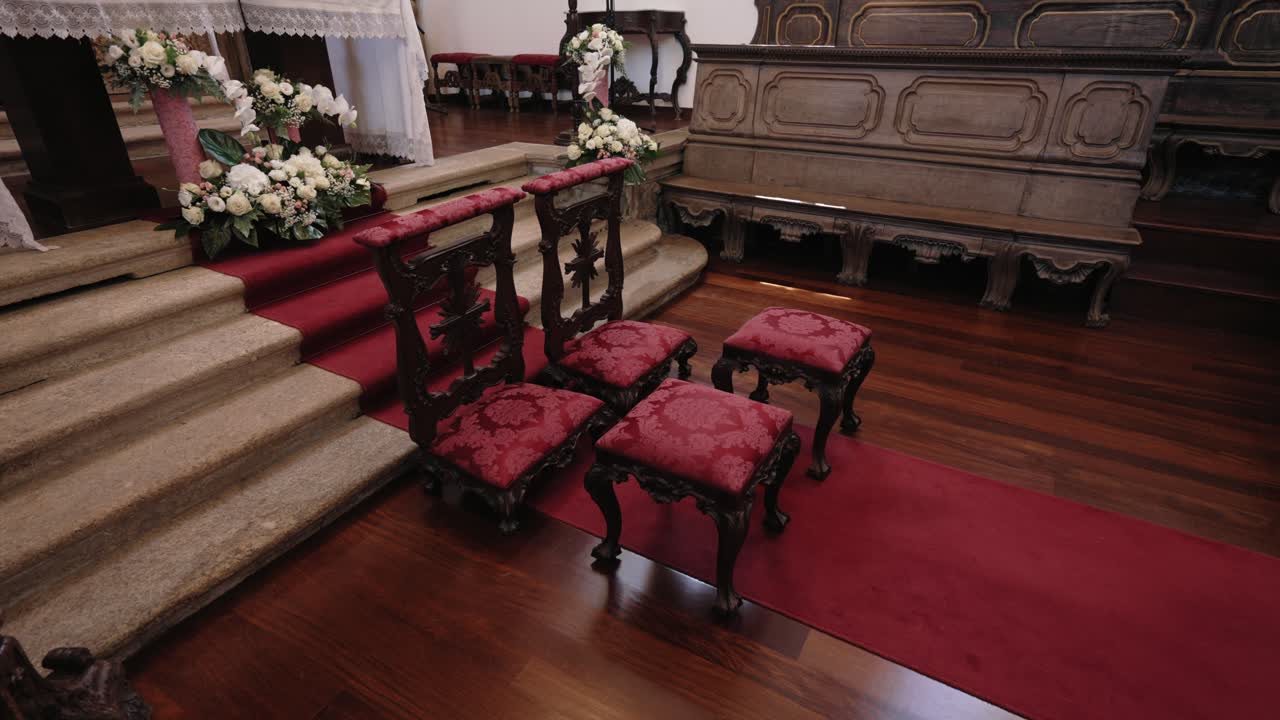 Ornate red cushioned chairs arranged at altar on red carpet inside decorated church