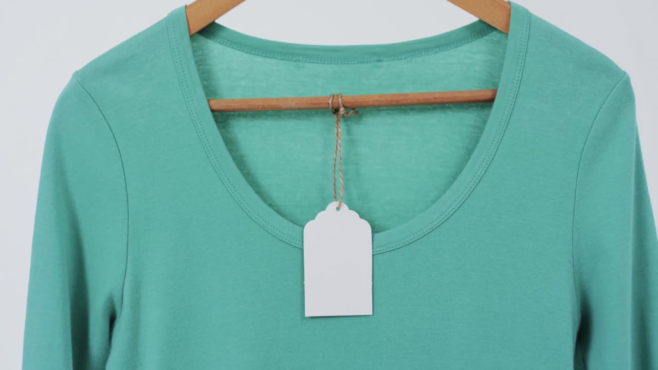Video of green t shirt with tag on hanger and copy space on white background