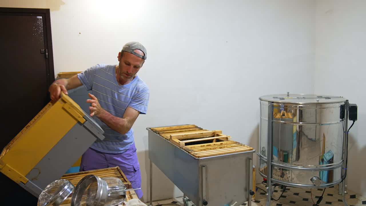 Apicoltore al lavoro con arnie e smielatore