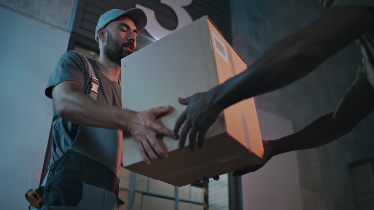 Outside of Logistics Retail Warehouse at Night Employee Giving Cardboard Box to Loader