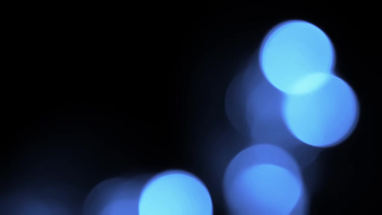 Luci bokeh blu che compaiono e si dissolvono su sfondo nero