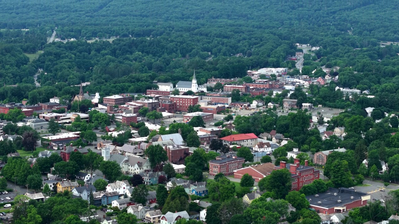 Paisaje urbano y colinas boscosas vistos desde la Torre Poets Seat en Greenfield, Massachusetts, EE. UU. Descenso aéreo, toma con inclinación ascendente.