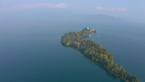 Fly-in-aerial-shot-revealing-the-vibrant-Isola-Del-Garda-in-misty-morning-light