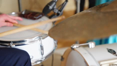 musician striking cymbals and drum head in studio captured in detailed slow motion