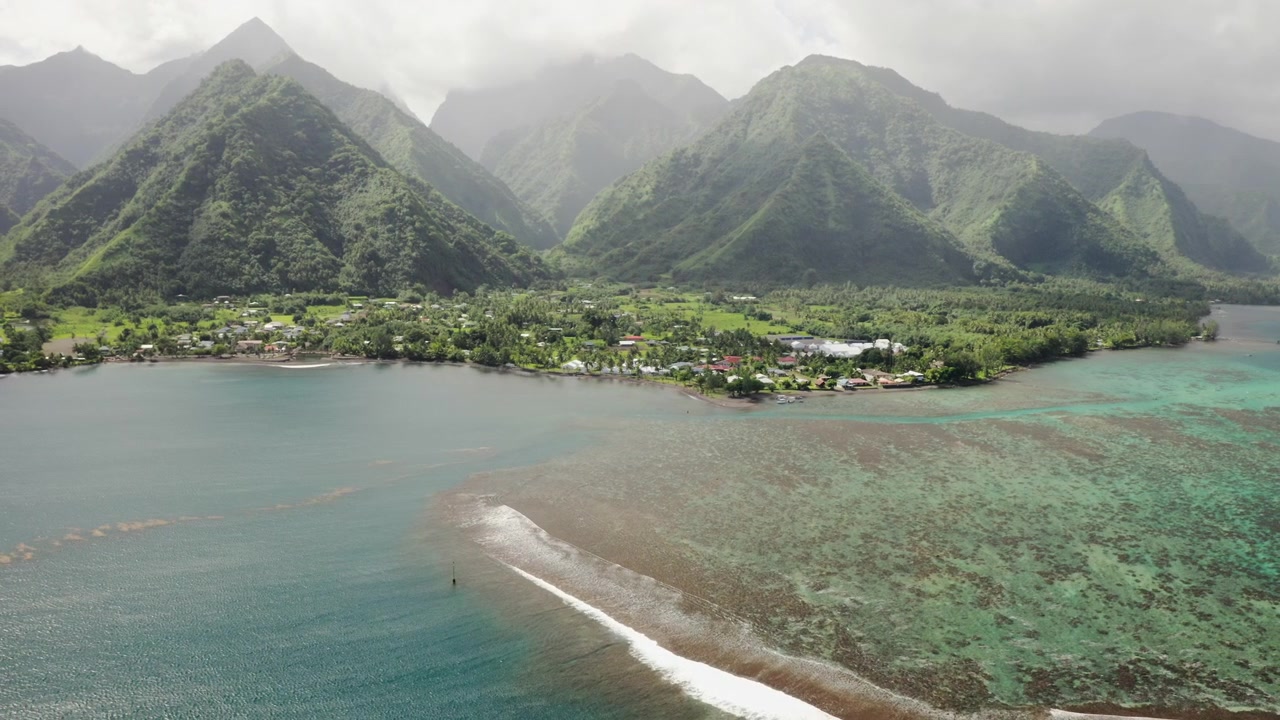 Tahiti, Teahupoo yakınlarındaki sisli yağmur ormanı vadisinden kıvrımlı bir nehri takip eden havadan çekim; yoğun yeşil bitki örtüsü uzaktaki Pasifik kıyı şeridine doğru uzanıyor.