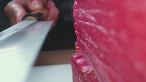 unrecognizable cook cutting raw tuna