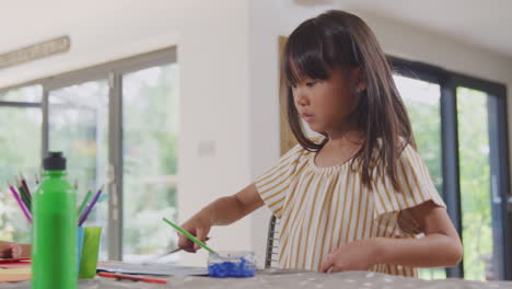 Madre-Asiática-Divirtiéndose-Con-Niños-Haciendo-Manualidades-En-La-Mesa-En-Casa