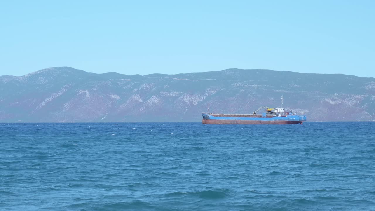 Cargo ship at sea with mountains in the background