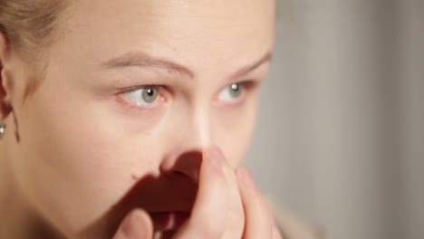 young woman is putting cosmetic cream on her face