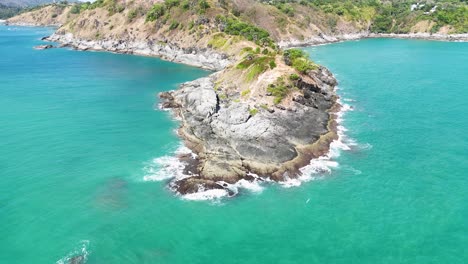 aerial footage showcasing the stunning coastline and rocky cliffs of promthep cape in phuket, thailand, under bright daylight