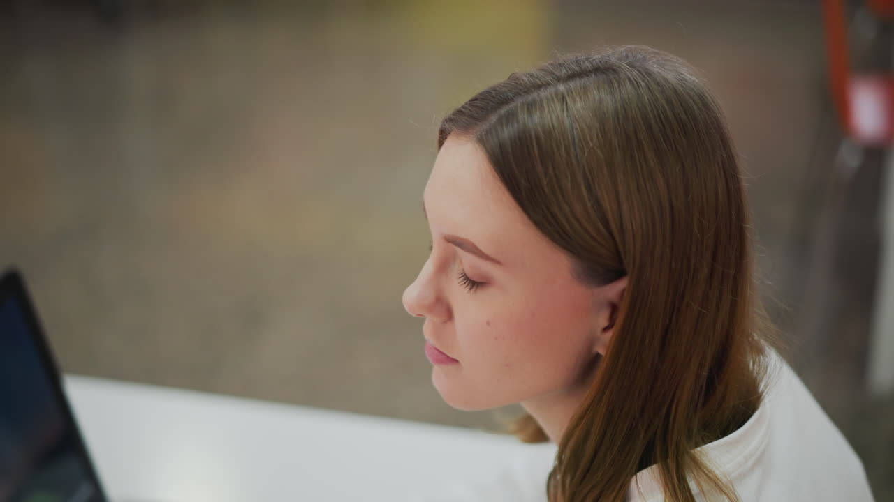 крупный план молодой женщины с задумчивым выражением лица, глядящей вперед в яркой внутренней среде с тонким цветным размытием фона и мягким освещением