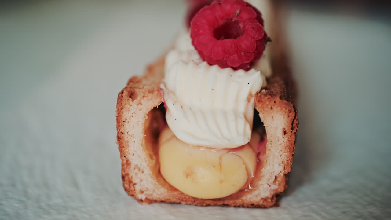 Close up of a gourmet pastry topped with cream, raspberries, and red currants
