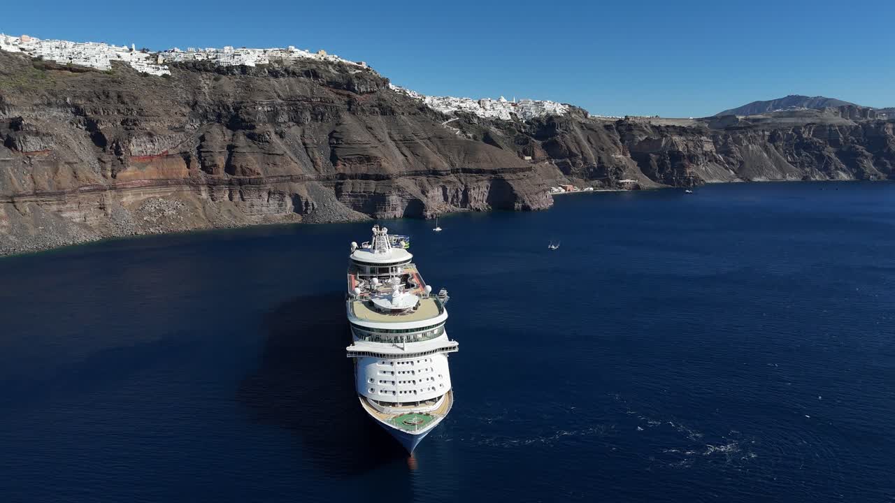 aerial view of large cruise ship off the coast of Santorini island, Greece with town of Fira in the background