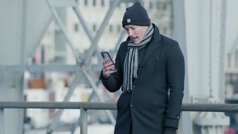 Hombre-Haciendo-Facetiming-Afuera-En-La-Fría-Ciudad-Usando-Su-Ropa-De-Invierno-A-La-Suave-Luz-Del-Día