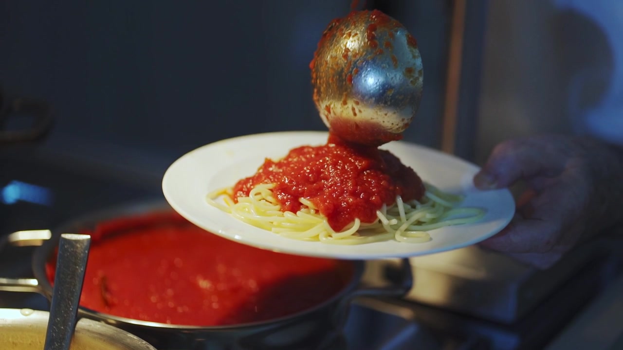 シェフがボウルの中で鮮やかな料理の材料を混ぜ合わせているクローズアップ。