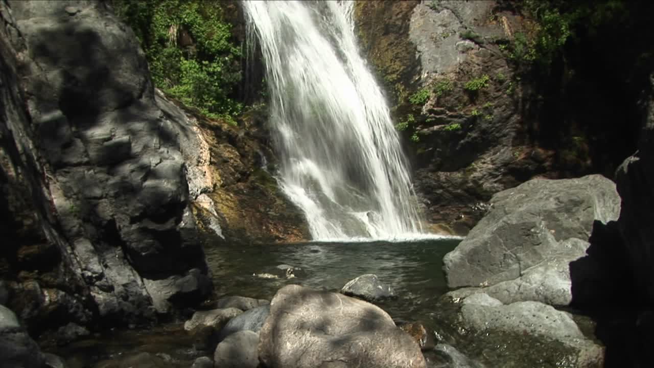 panup de una cascada que desemboca en una piscina reflectante en big sur california