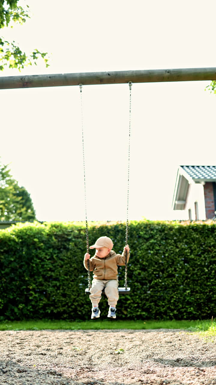 Bambino felice sull'altalena al parco in una splendida giornata estiva. Un bambino sorridente si dondola in un parco giochi in una calda giornata d'estate. Bambino all'aperto in un parco giochi.