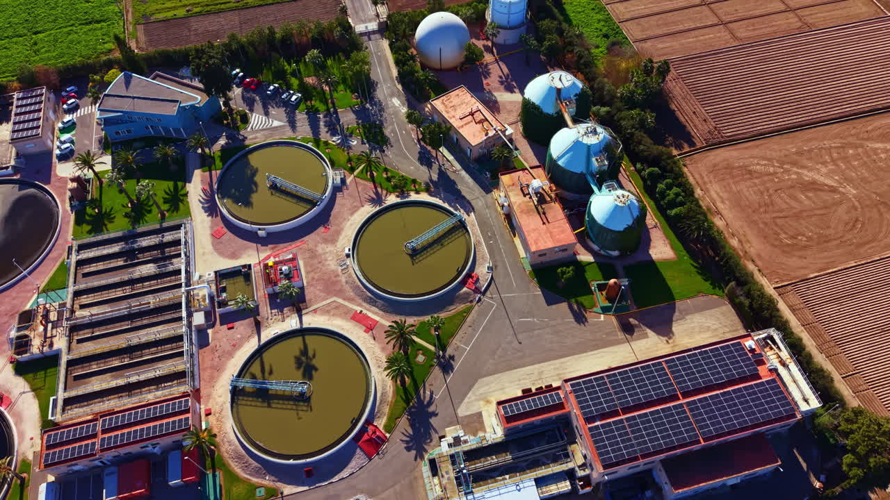 Water treatment facility operates with large tanks and solar panels in rural area during daytime with clear skies