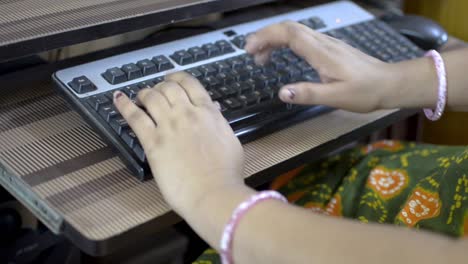 woman typing on keyboard of desktop pc computer close up top side view only hands visible