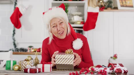 happy senior caucasian woman wearing santa claus hat, having video call