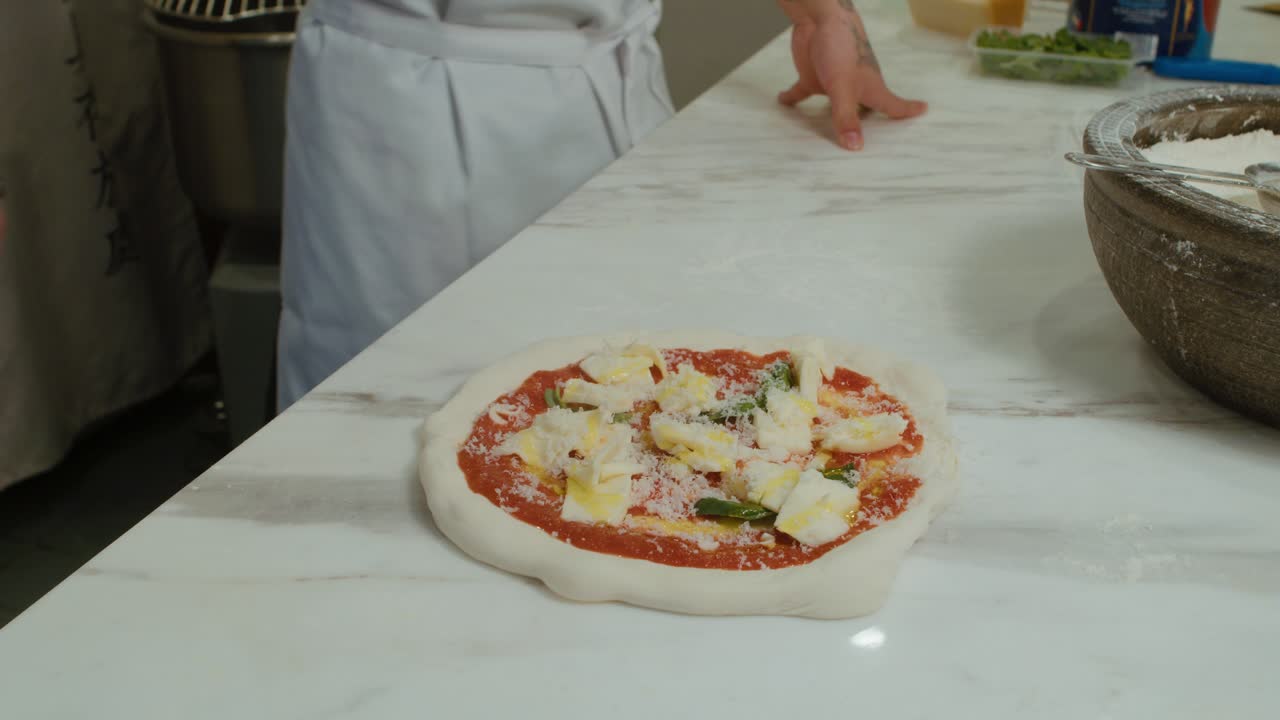 Adding olive oil on top of Neapolitan style raw pizza with other ingredients