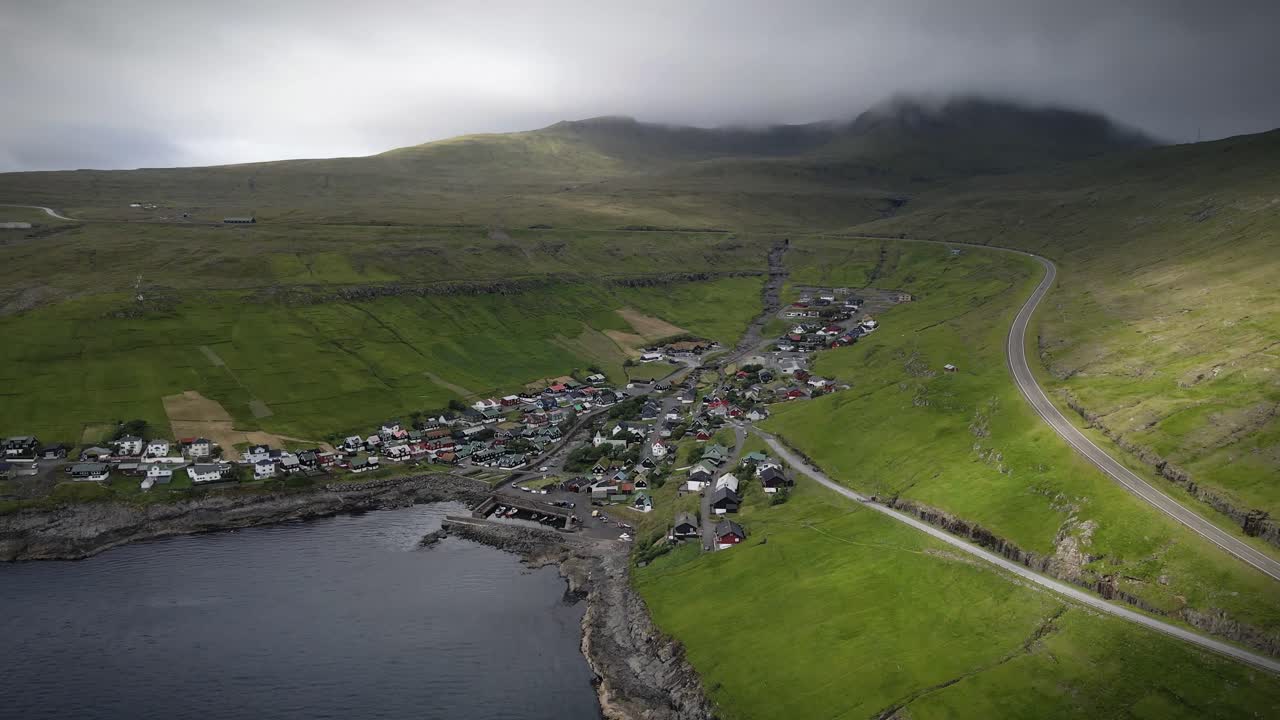 푸른 언덕 사이에 자리잡고 해안선을 내려다보는 페로 제도에 있는 그림 같은 마을인 kvívík의 공중 풍경.