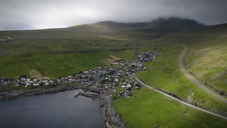 aerial view of kvívík, a picturesque village in the faroe islands, nestled among green hills and overlooking the coastline. the winding road adds charm to the serene natural surroundings