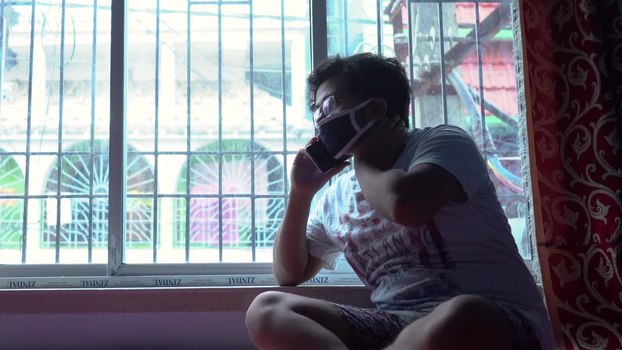 covid-19 코로나 바이러스 잠금, 자기 격리 및 사회적 거리 때문에 창가 근처에 집에 앉아 지루한 아시아 남성