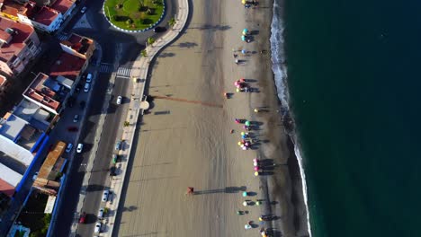 Drone-footage-from-height-filming-down-on-a-beach-near-a-road-in-Spain