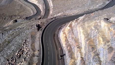 drone volando sobre la carretera de la montaña del desierto en la montaña jebel jais en los emiratos árabes unidos - toma aérea