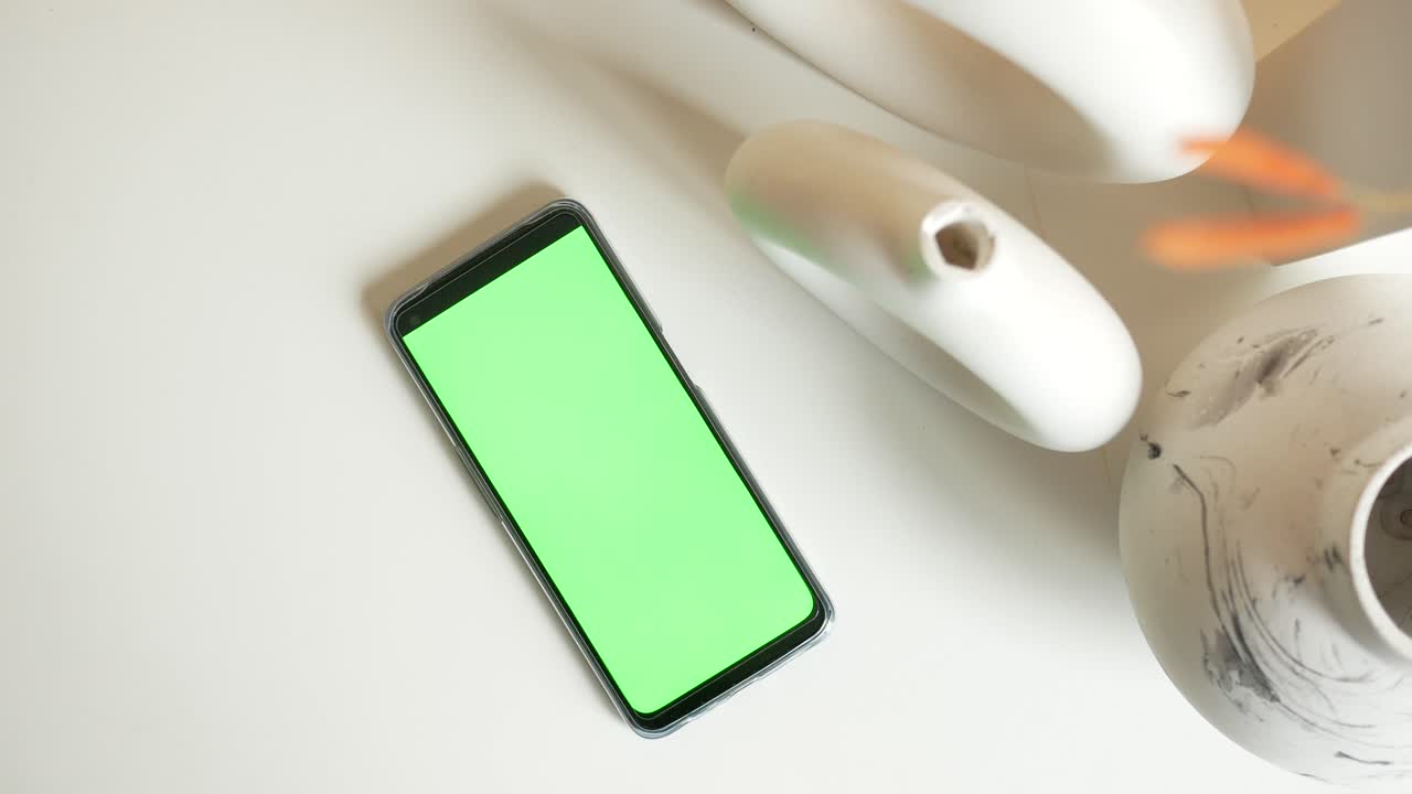 teléfono inteligente con pantalla verde y jarrones decorativos