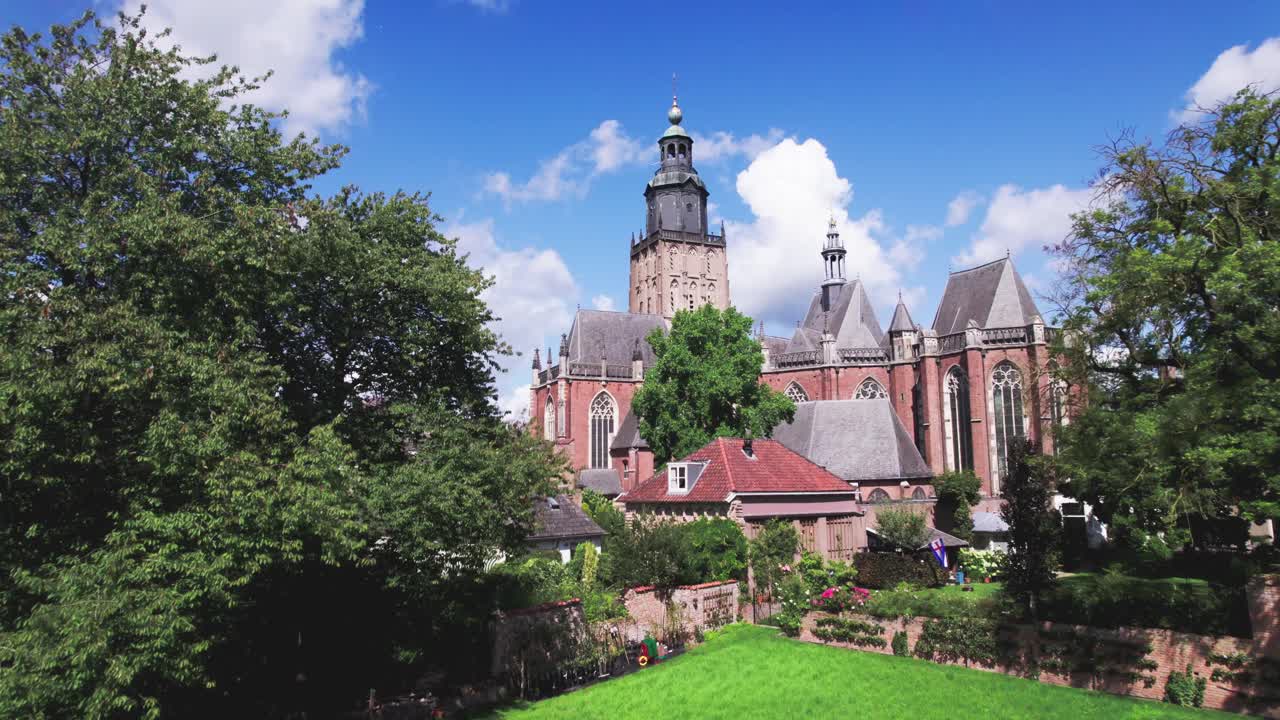 Community garden of medieval town Zutphen, The Netherlands in the foreground with Walburgis kerk church tower rising above behind historic city wall against a blue sky. Aerial picturesque Dutch city