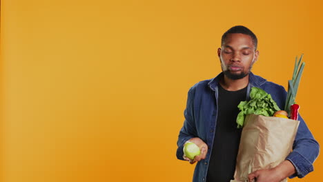 african american vegan guy taking a bite from a ripe natural green apple