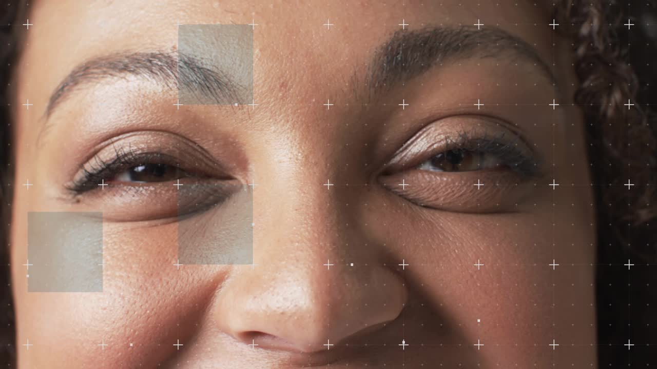 Woman holding gaze, blinking and smiling as markers track motion, causing shifting patches for VFX