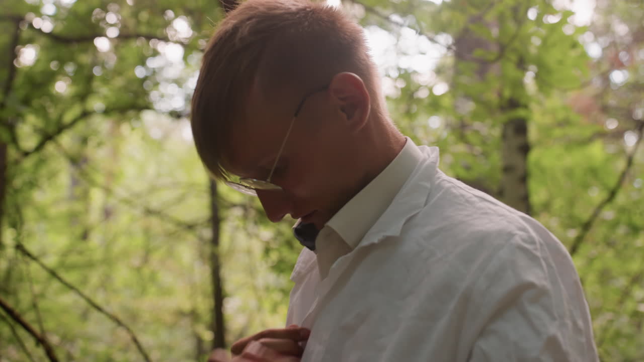 Young botany student adjusting white coat in forest surrounded by lush greenery and natural light, highlighting field research preparation, outdoor scientific exploration, and ecological study