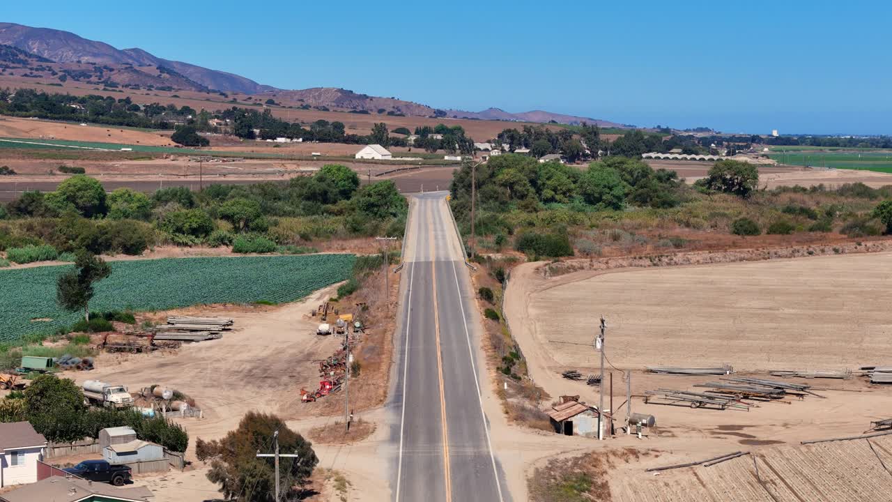 Straight rural road cutting through fields and farmland in Salinas Valley, California