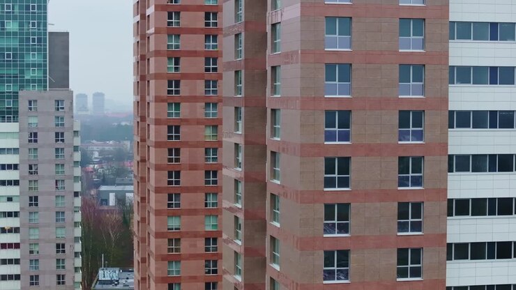 Drone faz uma passagem cinematográfica ao longo de fachadas de prédios modernos em Pleskodāle